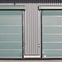 Grande façade pliante à côté de deux stabulateurs verts fermés sur un entrepôt d'engrais