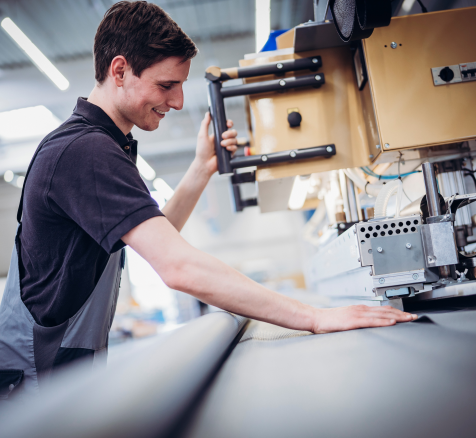 Fil HUESKER pour textiles techniques Un employé utilise une machine à découper chez HUESKER