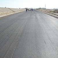 Pose de grilles HaTelit sur la surface de la route avant l'asphaltage par les ouvriers du bâtiment