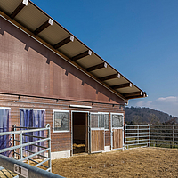 Bâtiment d'élevage avec filet brise-vent brun Lubratec pour un meilleur climat d'élevage