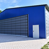 Façade pliante grise sur le pignon d'un gymnase bleu