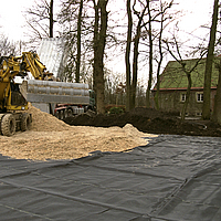 Une pelleteuse installe la couche de séparation Lubratec dans le sol