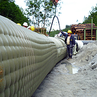 Les ouvriers remplissent l'Incomat® Pipeline Cover avec une pompe à béton via la tubulure de remplissage