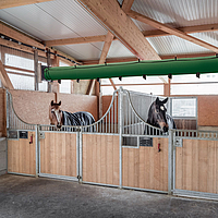 Lubratec Tube Cool sur le plafond d'une écurie et au-dessus de deux boxes avec des chevaux