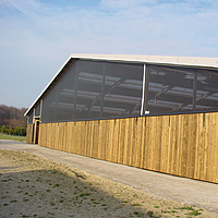 Vue extérieure d'une écurie avec un système de protection contre le vent Lubratec installé