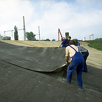 Ouvrier lors du processus de pose de la natte de bentonite HUESKER sur un chantier d'étanchéité